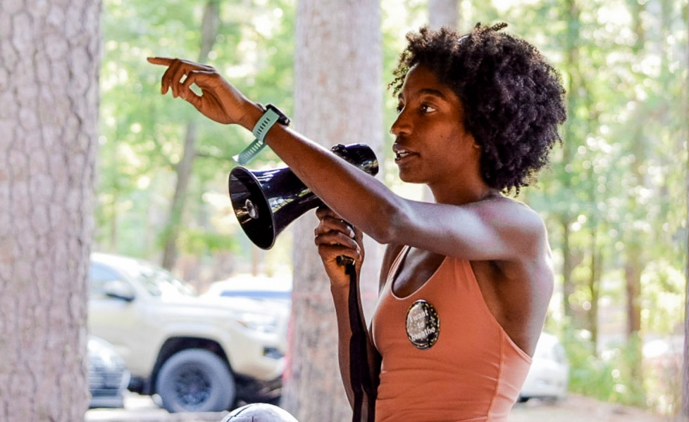 A person speaks into a megaphone at an outdoor event.