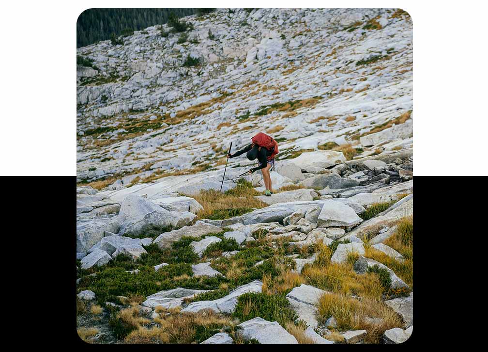 A runner doubled over catching their breath on rocky terrain.