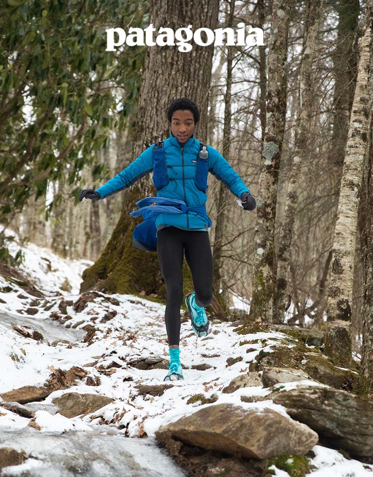 A person jogs down a rocky trail that’s covered in snow.