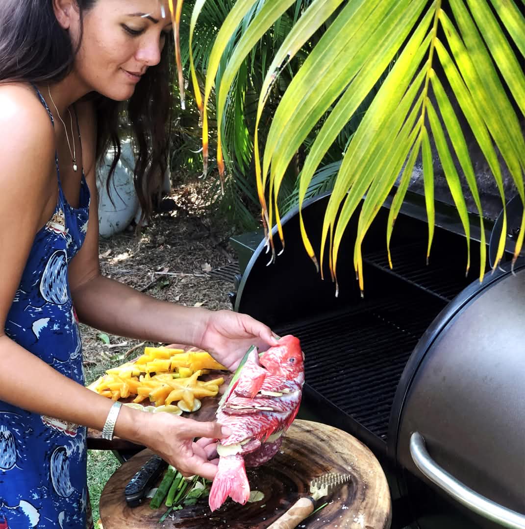 A person preps a fish to cook on a grill.
