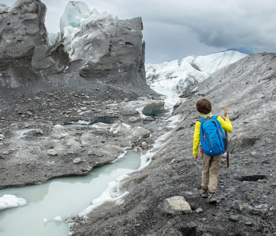 A kid hikes across a glacier.