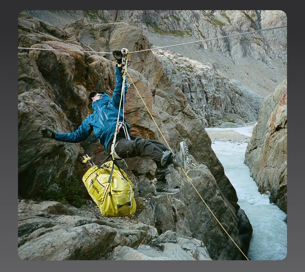 A person crosses a chasm hanging from a rope.