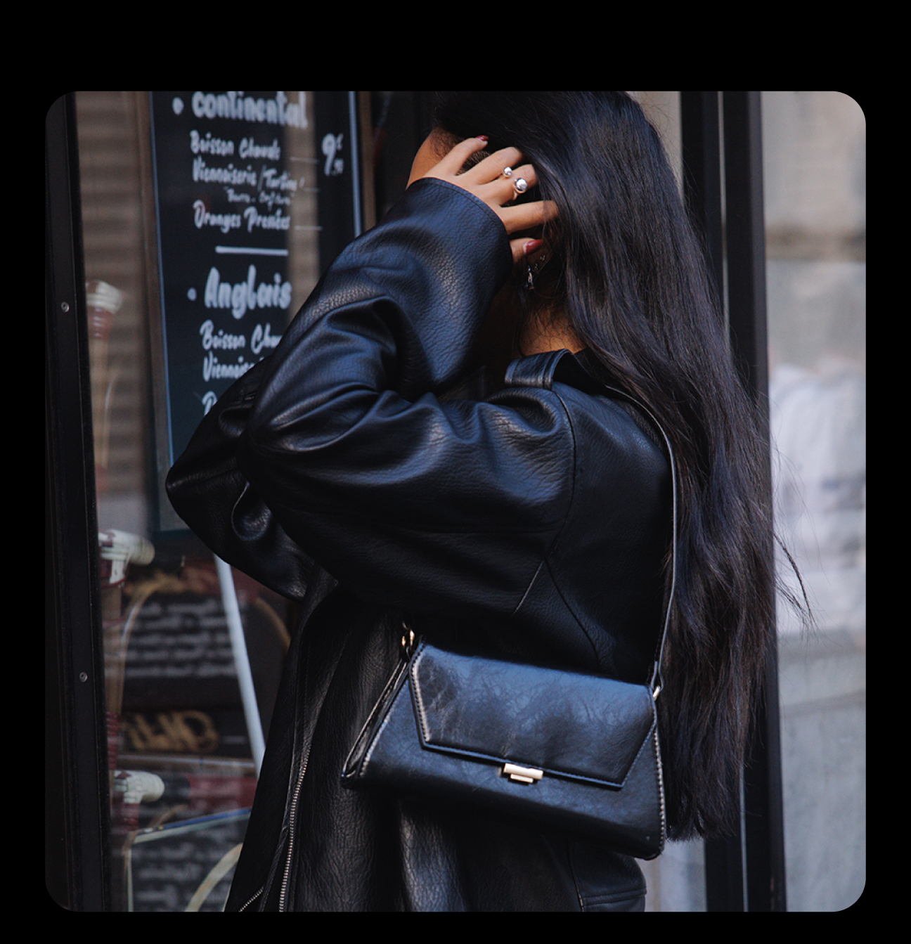 Woman wearing a black jacket with a black over the shoulder bag