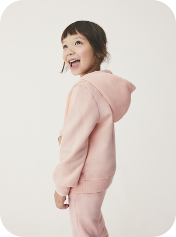 A young girl wearing a pink tracksuit set