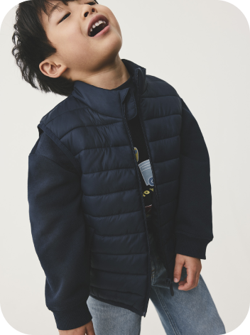 A young boy wearing a navy padded jacket 