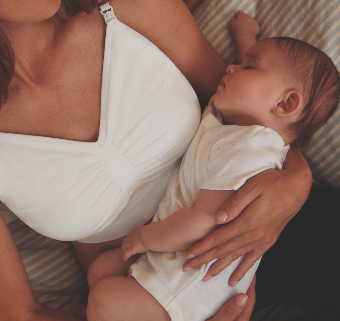 A women holding a baby wearing a white babygrow