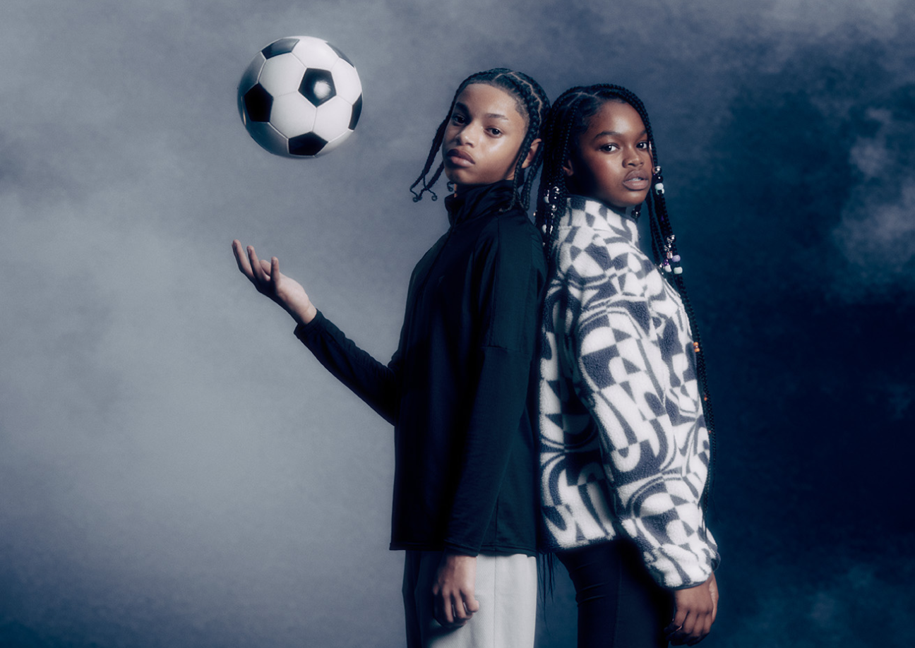 A young boy wearing a navy jacket throwing a ball with a young girl wearing a black and white fleece jacket 