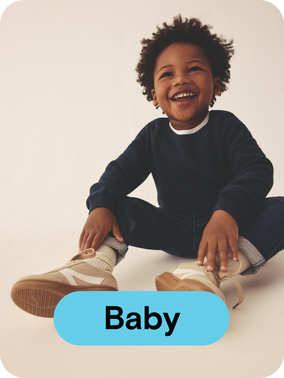 Young boy smiling wearing a navy jumper and navy jeans