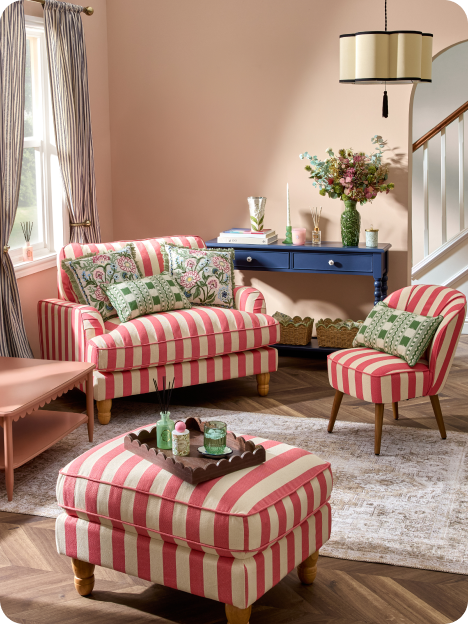 A living room containing a pink and white stripe furniture set with green decor 