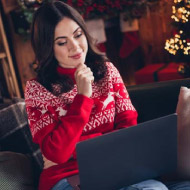 Senhora com camisola temática de Natal a observar o computador.