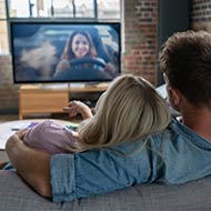 Casal vê televisão.