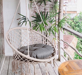 Hängesessel weiß in runder Form aus Flechtwerk mit Zierquasten und grauer Polsterung