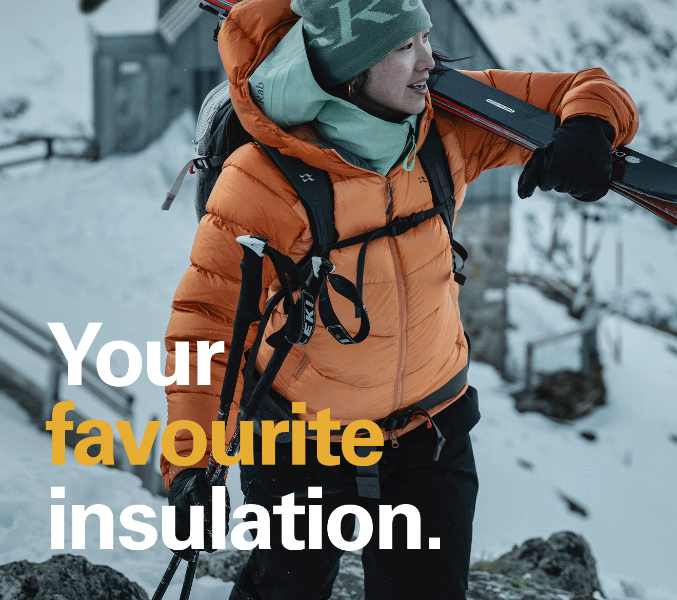 'Your favourite insulation.' text over the image of a women walking as she carries her skis, while wearing a Rab jacket and hat.