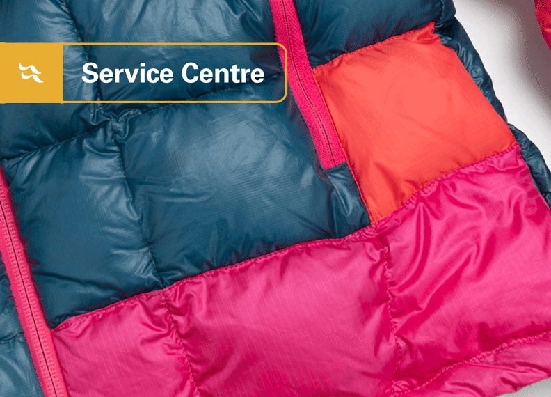 An alpinist donning a synthetic jacket on a snowy mountainside.