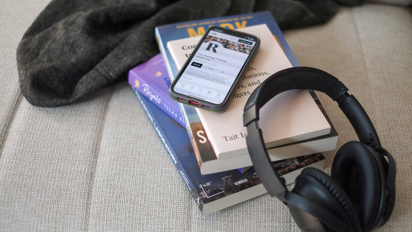 A phone showing our Readings Podcast soundcloud page, on top of a stack of books by authors that have featured on the Readings podcast.