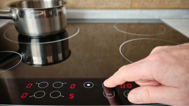 Hand adjusting controls o an induction stovetop.