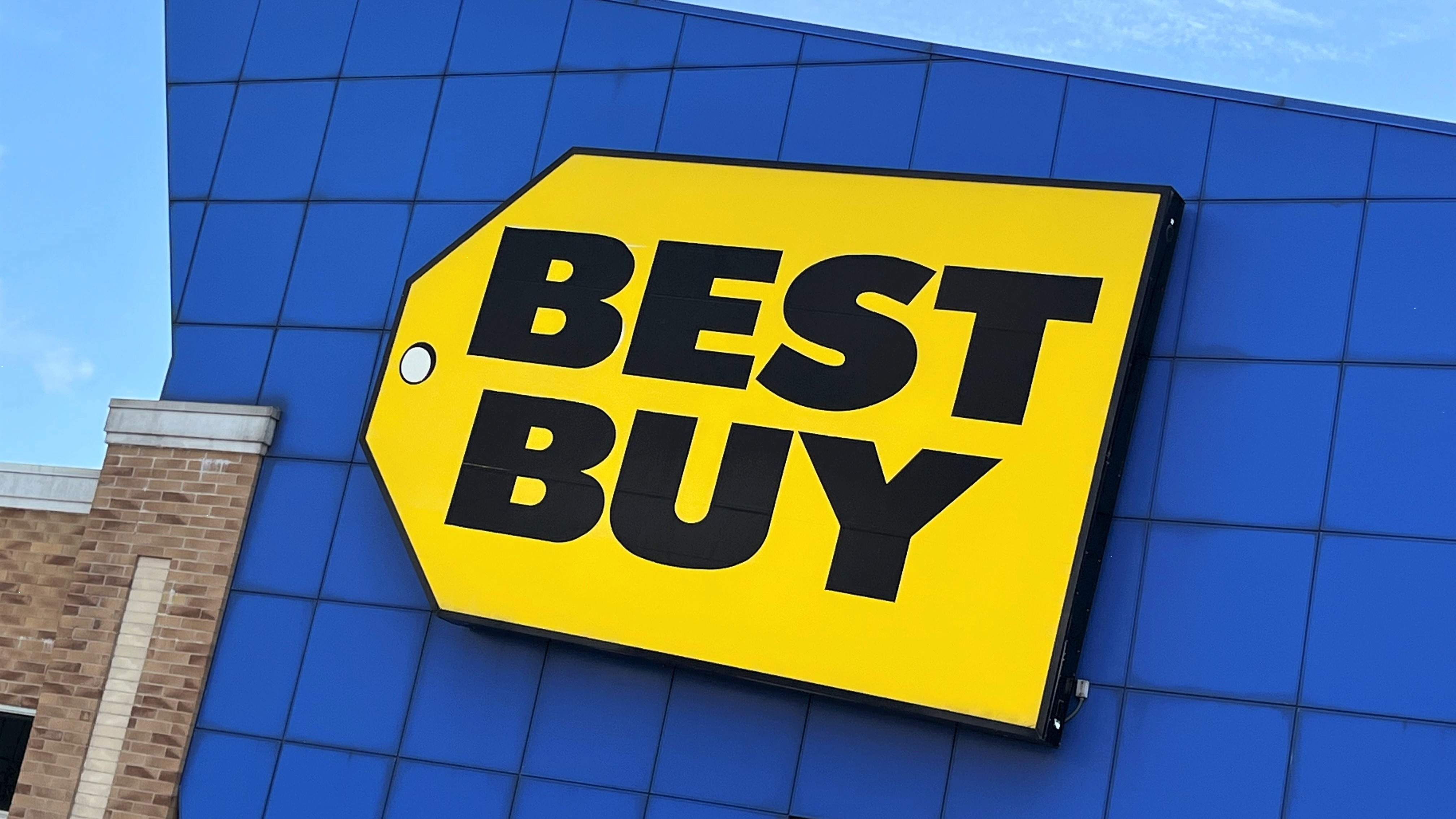 Blue building with yellow price tag best buy logo on it. The words Best Buy are on the price tag in black type. 