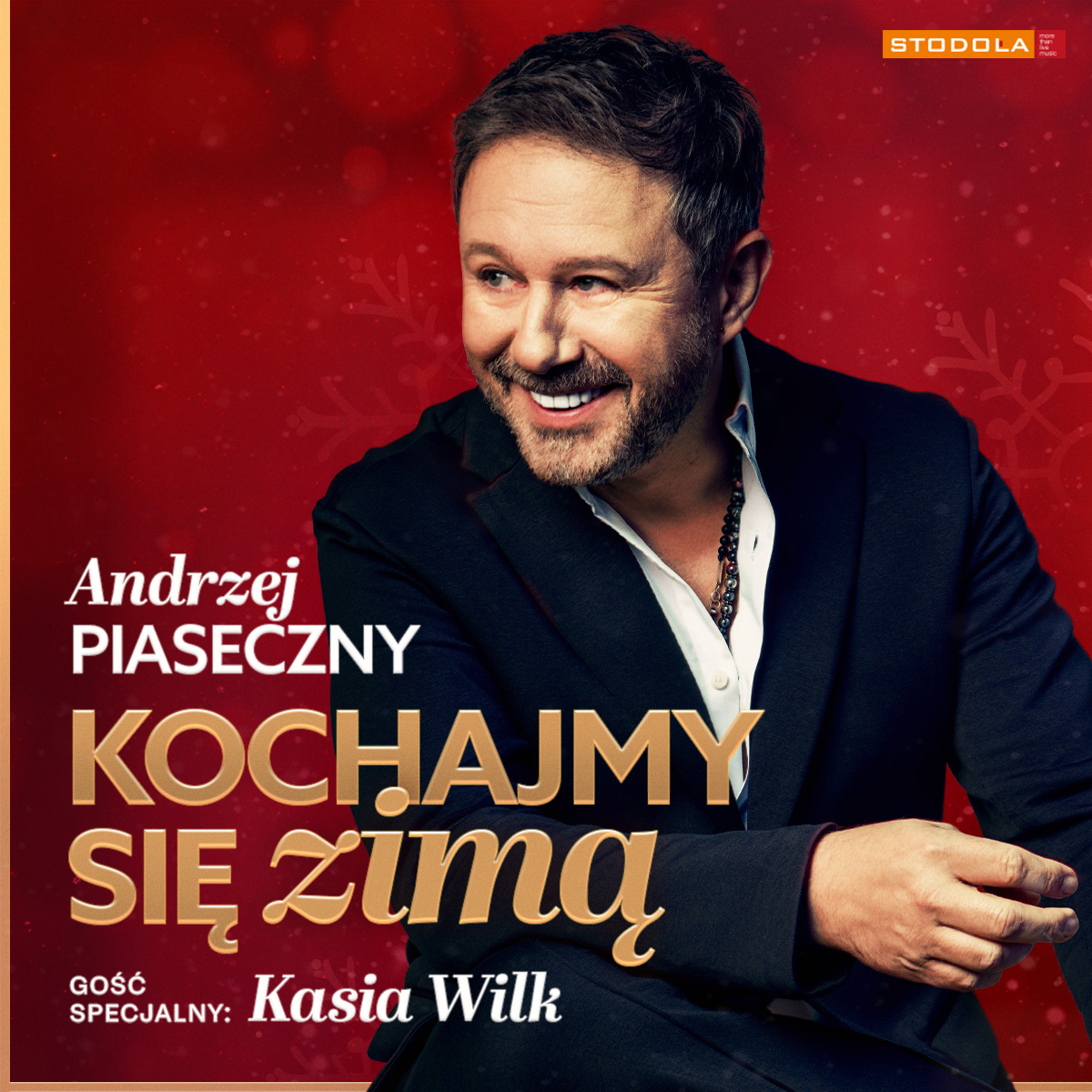 Concert poster of a smiling male singer in a dark suit against a red festive background with gold text "Kochajmy się zimą"
