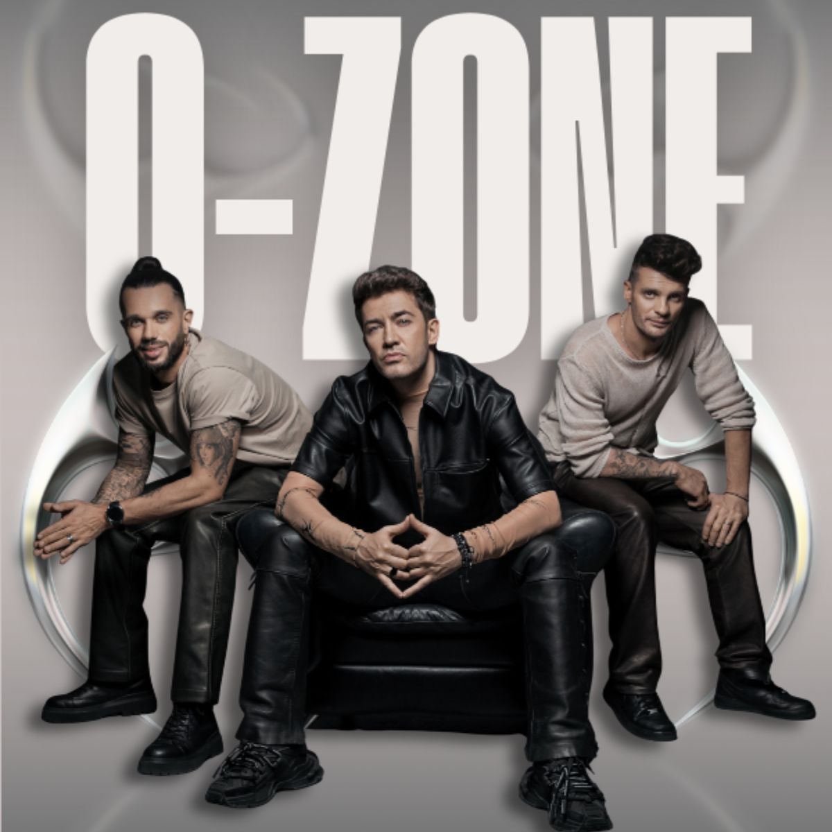 Three-member pop trio seated in front of large O-ZONE logo, leather and casual outfits, stylised studio album cover promotional photo