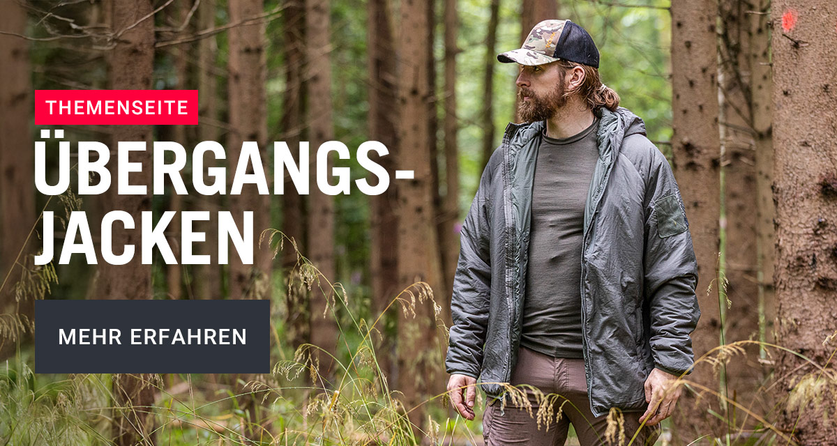 Mann mit Bart, Cap und Übergangsjacke steht im Wald – TACWRK Themenseite Übergangsjacken.