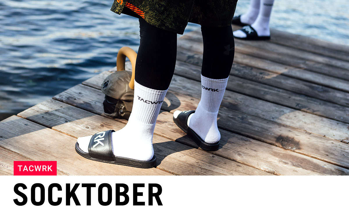Weiße TACWRK Socken mit Slides auf einem Holzsteg am Wasser – sportlicher Socktober-Vibe mit Under Armour Leggings.