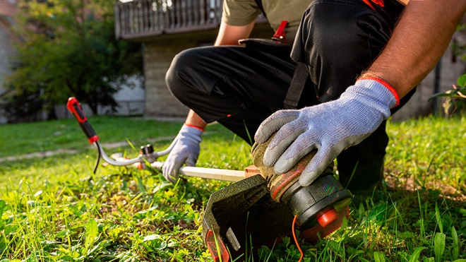 Jardinier nettoyant son coupe bordure