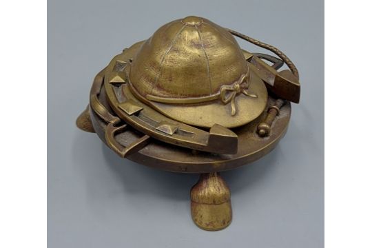 A brass inkwell decorated with a riding cap