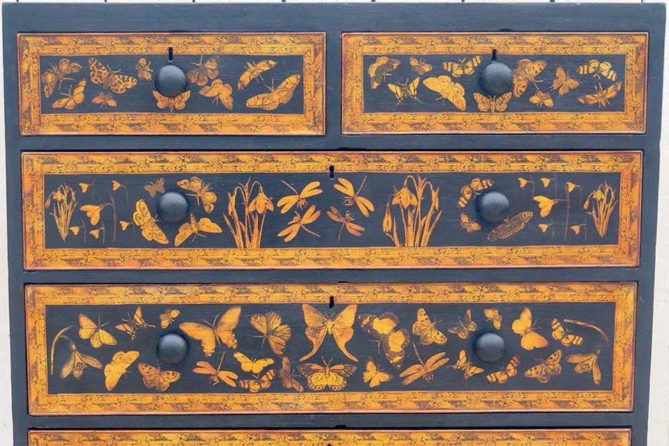 A 19th century chest of drawers painted black with decoupage