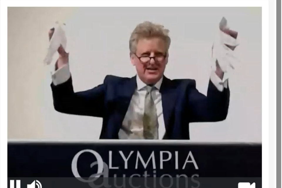 Auctioneer Adrian Biddell holding up a pair of white gloves