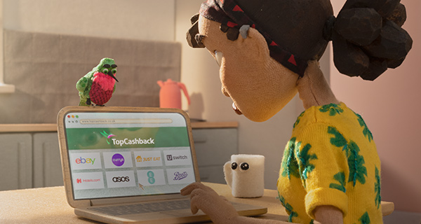 Image of person browsing TopCashback with a hummingbird sitting at the top of their screen