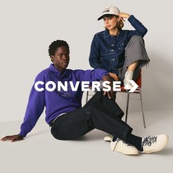 Due persone in abbigliamento casual; una seduta sul pavimento in un maglione viola, pantaloni neri e stivali bianchi; l'altra su sedia in giacca di jeans, pantaloni grigi e cappellino bianco.