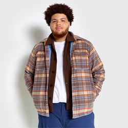 Giacca a quadri con tonalità marroni, blu e arancioni, chiusura frontale con bottoni e due tasche sul petto, indossata sopra una camicia marrone e una t-shirt bianca.