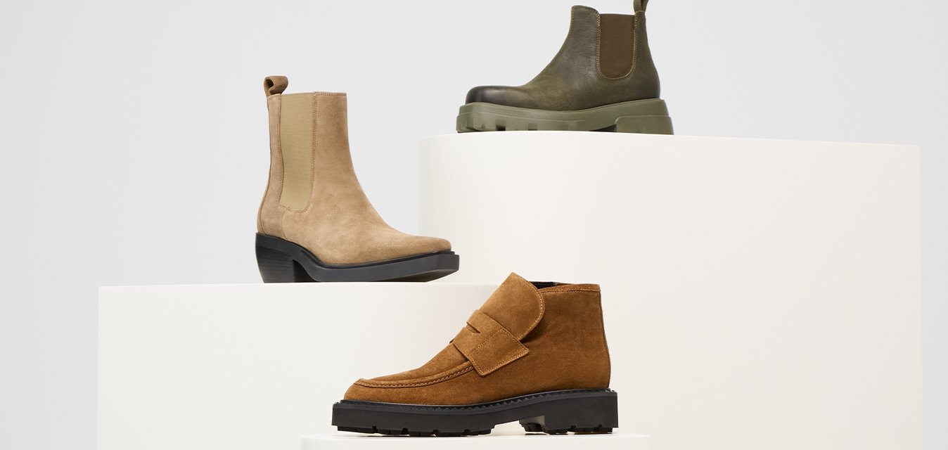 Tre stivali in suede: beige chiaro con una suola nera, verde oliva con una suola spessa e marrone con un dettaglio a cinturino e suola nera testurizzata.