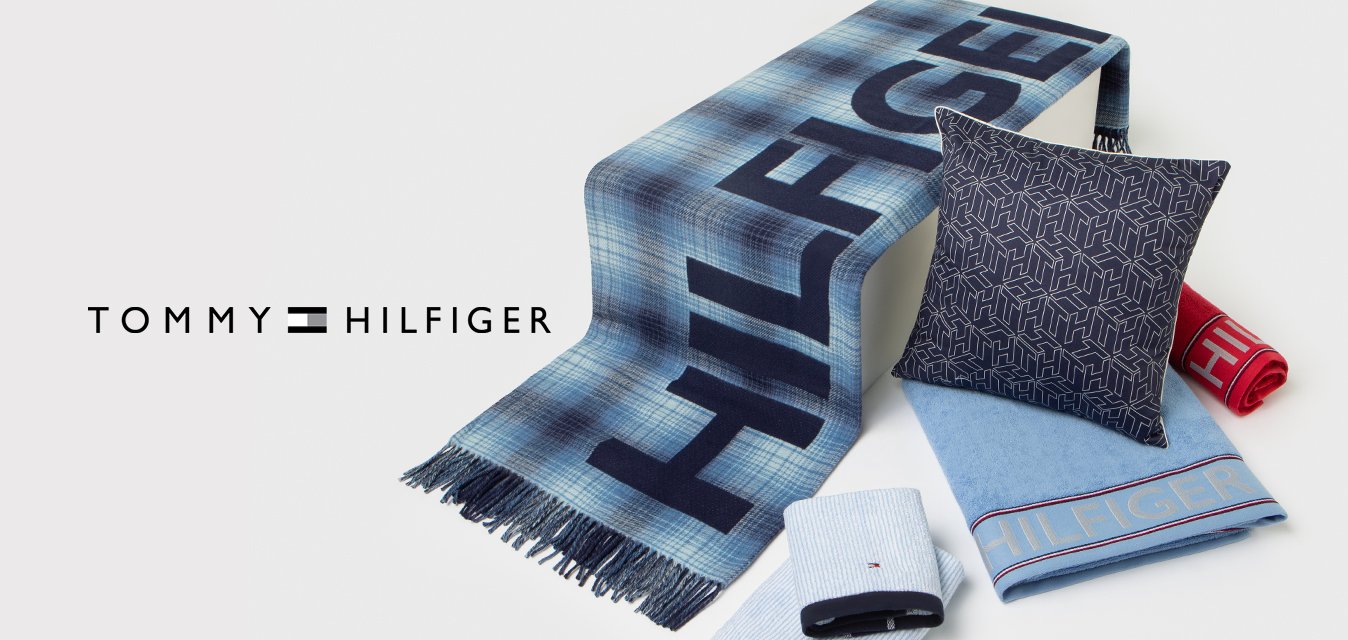 Coperta a quadri blu con frange, cuscino a fantasia navy, due asciugamani a righe e un asciugamano rosso, tutti con il marchio 