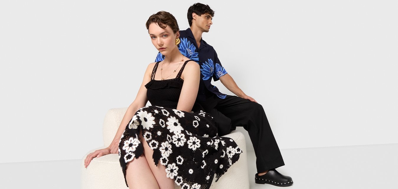 Gonna floreale in bianco e nero, top nero a trama, camicia floreale blu e pantaloni neri. Superfici lisce e motivi a contrasto presenti.