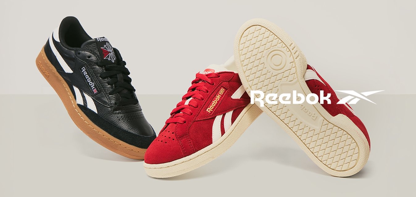 Sneaker Reebok in pelle nera e suede rossa mostrati affiancati, una scarpa rossa mostra la suola con un motivo testurizzato.