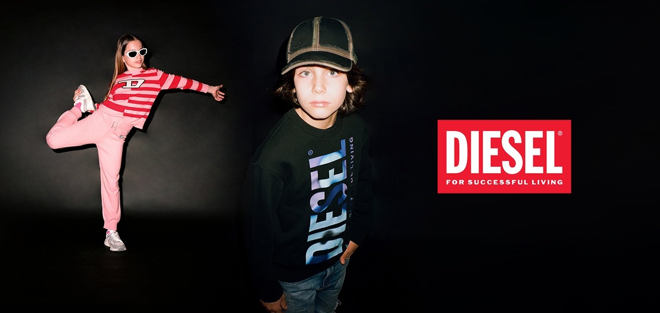 Una ragazza indossa un crop top a righe rosse e pantaloni jogger rosa con scarpe da ginnastica bianche. Un ragazzo in un felpa Diesel nera si trova vicino, guardando verso la macchina fotografica.