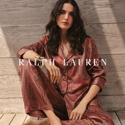 Set di pigiami in raso rosso con motivo paisley, bottoni frontali, maniche lunghe e vestibilità rilassata, abbinato a un semplice braccialetto con polsino, su un ponte di legno.