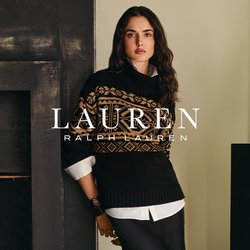 Donna in nero, maglione con motivo beige e lunga gonna nera si trova vicino a un caminetto scuro e a una scultura astratta su un piedistallo vicino alla finestra.