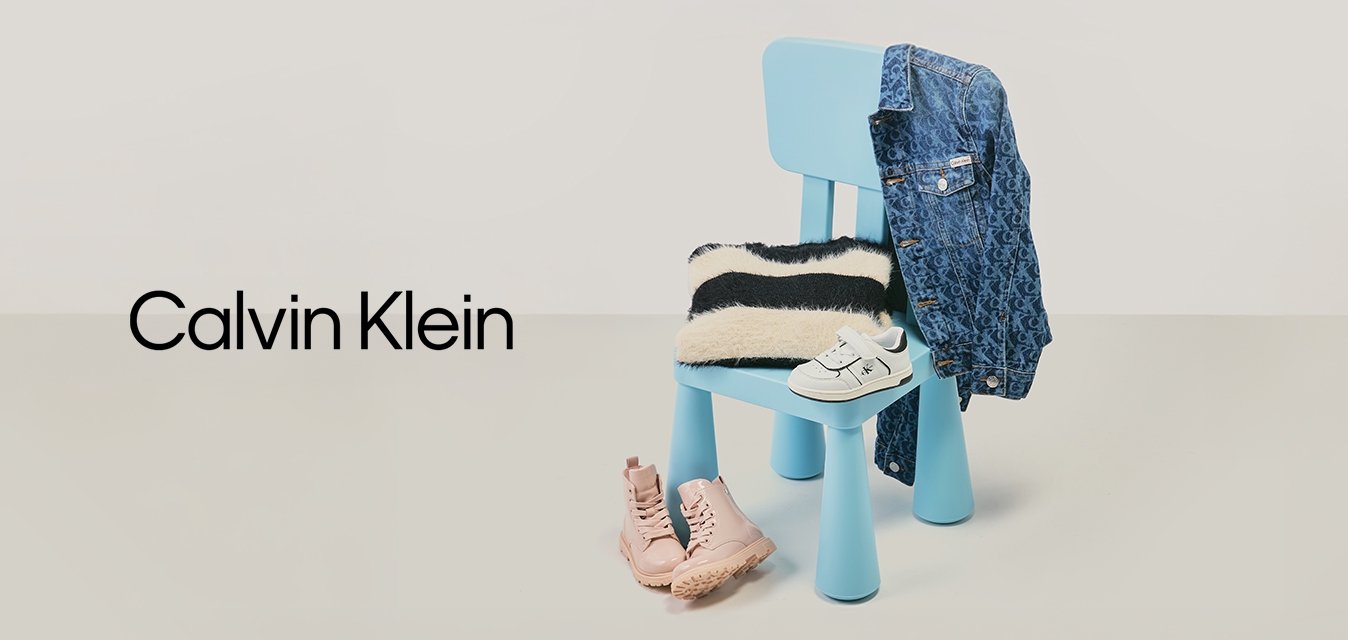 Sedia blu con maglione a righe bianco e nero, giacca di jeans appesa allo schienale, scarpe bianche per bambini sulla seduta e stivali rosa sul pavimento.