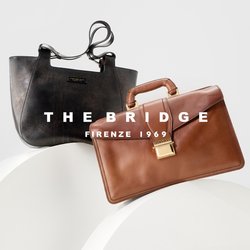 Due borse in pelle, una tote nera con spallacci e una valigetta marrone con manico e chiusura dorata, esposte su supporti bianchi curvi.