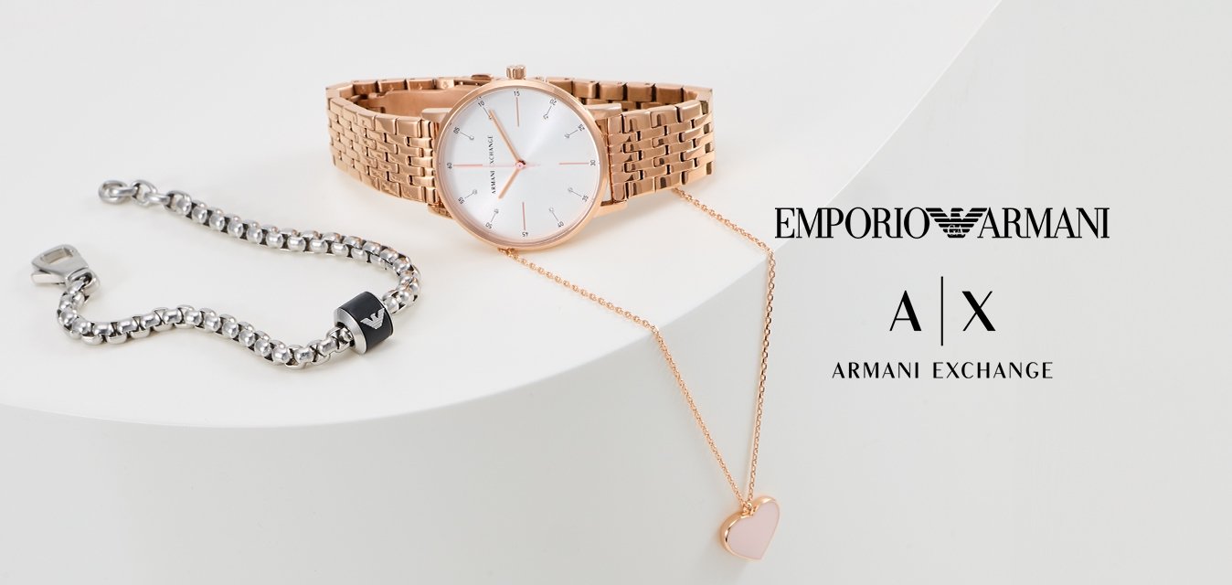 Orologio in oro rosa con cinturino a rete e quadrante bianco, bracciale in argento con accento nero, e collana con pendente a forma di cuore in oro rosa.