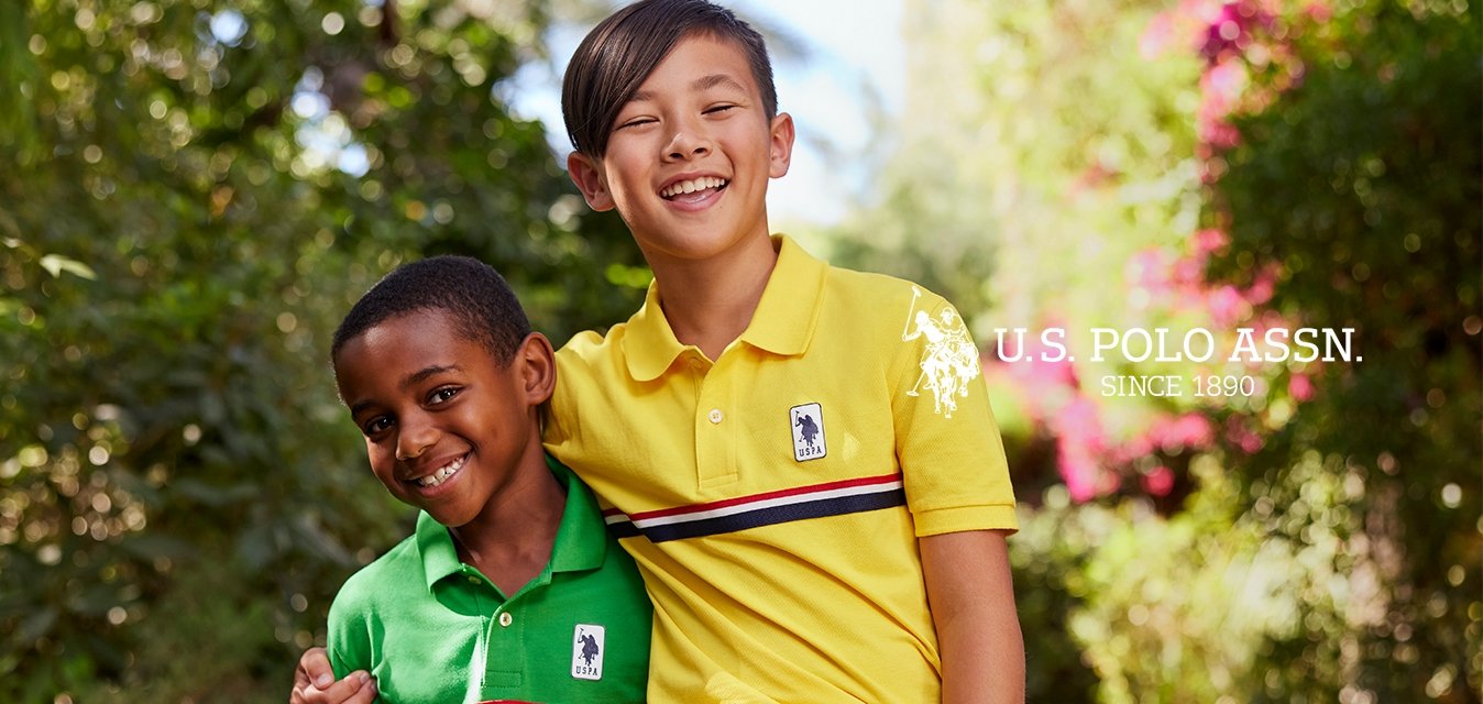 Due bambini sono all'aperto, indossando polo: una verde con un logo e strisce, l'altra gialla con un logo e strisce, entrambe a maniche corte.