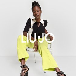 Top nero a costine con colletto bianco decorato e cravattino, abbinato a pantaloni larghi gialli e tacchi neri con straps.