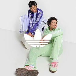 Due persone in abbigliamento sportivo: una in un tuta leggera di colore viola, l'altra in verde menta. Entrambe indossano scarpe da ginnastica casual e sono sedute su una superficie bianca.